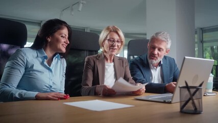 Diverse group of co-workers chatting about upcoming collaboration project holding documents