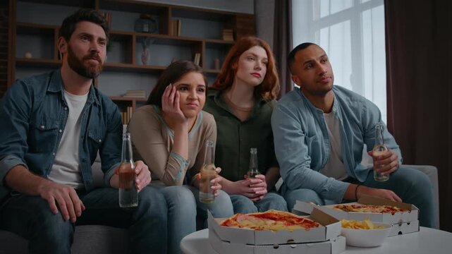 Multiethnic four friends watching TV sport program sad worried supporting favorite sport team upset with lost loosing failure watch television match with beer pizza on home party multiracial men women
