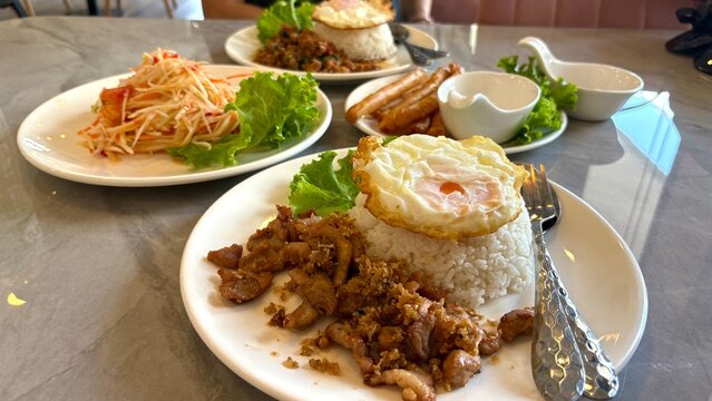 Close up fried pork and fried egg and papaya pok pok in background , thai food image.