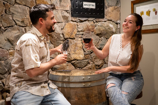 Pareja compartiendo vino tinto en la sala de degustaci&oacute;n de una bodega