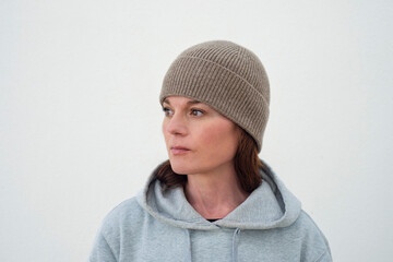 Portrait of a woman in a beanie hat and hoodie looking thoughtfully to the side