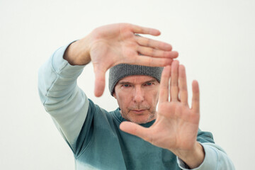 man in a knit hat making a frame with his hands, photographic framing