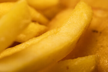 Macro close-up of golden frozen french fries. Detailed texture of raw potato sticks ready for cooking. An ideal background for fast food and semi-finished products.