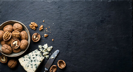 Blue cheese and walnuts on dark slate with a knife and copy space, overhead view.