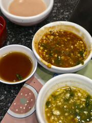 Delightful variety of Asian dipping sauce in white bowl. Flavorful spicy, sweet, and savory condiment perfect for hot pot or barbecue meal. Close up view of tasty dressing