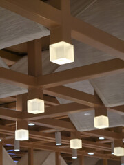 Tranquil and warm architectural interior design with modern geometric wood beam ceiling and glowing cube lamps creating an inviting and peaceful ambiance for any space