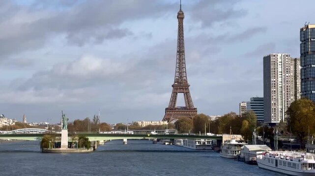 Peaceful view of the Eiffel Tower and Paris Statue of Liberty on the Seine River calm water gentle clouds and warm daylight creating cinematic urban scenery and travel atmosphere