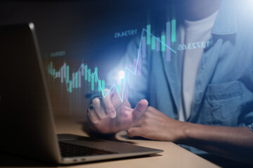 A man is using a laptop or smartphone to stock trading graph, graphic overlay laptop keyboard, finance and investment concept. Economy trends for business, financial charts and digits.