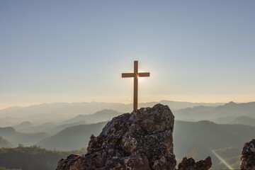 Silhouettes of crucifix symbol on top mountain with bright sunbeam on the colorful sunset sky background