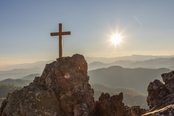 Silhouettes of crucifix symbol on top mountain with bright sunbeam on the colorful sunset sky background