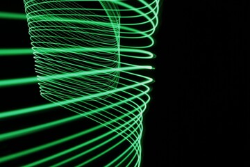 Long exposure light painting photography. Swirls of green light in parallel lines against a black background