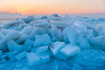 Ice chunks on a frozen lake at scenic sunrise with beautiful light and cold winter background. © artifirsov