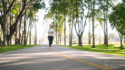 Asian adult woman runs outdoor park path fitness exercise for healthy living wellbeing energetic activity morning nature green environment