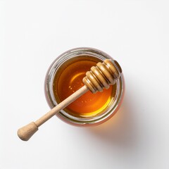 Top view of a glass jar of golden honey with a wooden dipper on a clean white background.