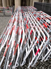 A stack of folding metal barriers with red and white stripes on a city pavement