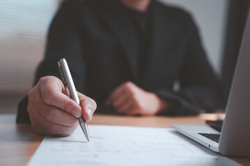 Businessman holding a pen and signing a document representing authorization paperwork approval legal agreement and formal documentation showing the concept of responsibility and professional workflow