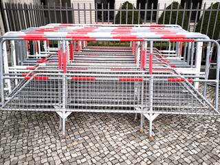 A stack of folding metal fencing with red and white stripes on a paving stone