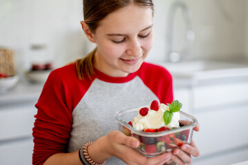 Smiling Girl Holds A Bowl Of Fruit Salad At Home In The Kitchen