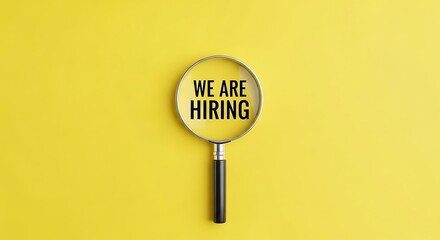 Magnifying glass reveals we are hiring message on bright yellow background for recruitment