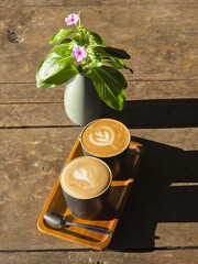 Relaxing top view of two coffee cups with latte art on wooden tray. This cozy morning scene on...