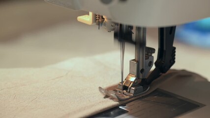 Sewing machine stitching fabric with needle and presser foot close-up