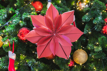 Red Origami Poinsettia Flower on a Brightly Lit Christmas Tree