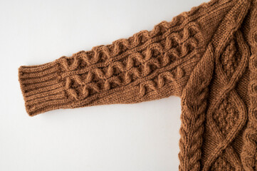 Knitted brown wool children's sweater, cardigan with buttons, pullover on light background top view. Autumn winter cozy warm cotton sweater with large pattern ornament. Stylish clothes fashion, mockup
