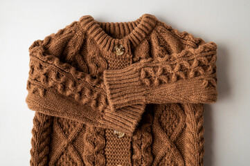 Knitted brown wool children's sweater, cardigan with buttons, pullover on light background top view. Autumn winter cozy warm cotton sweater with large pattern ornament. Stylish clothes fashion, mockup