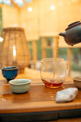 Close-up of a traditional Chinese Gongfu tea ceremony. A stream of fragrant oolong tea is being poured from a clay Yixing teapot into a simple ceramic teacup. Calm and mindful moment. 
