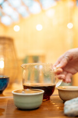 A moment of pouring hot tea in a traditional setting. The focused stream of freshly brewed tea connects the teapot and the cup, symbolizing ritual and refreshment.