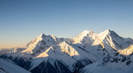 Wide panoramic view of majestic snow-capped mountains at sunrise or sunset, with warm golden light illuminating the peaks against a clear blue sky, symbolizing adventure, wilderness, and nature