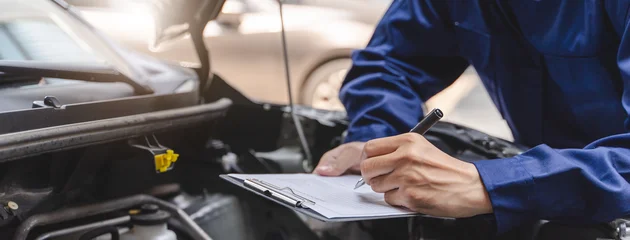 Fotobehang Muziek Auto check up and car service shop concept. Mechanic writing job checklist to clipboard to estimate repair quotation to client at workshop garage.  © Pormezz
