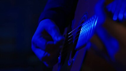 A person plays a guitar, with blue lighting creates an intimate and musical atmosphere Stock video