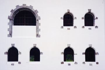An old antique window with an arch above it like a dome on a white building. The concept of an old building.