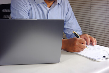 A person looks at a chart report on a laptop and then checks off the task list and budget list....