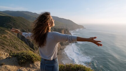 Young caucasian female embracing freedom on coastal cliff with scenic ocean view