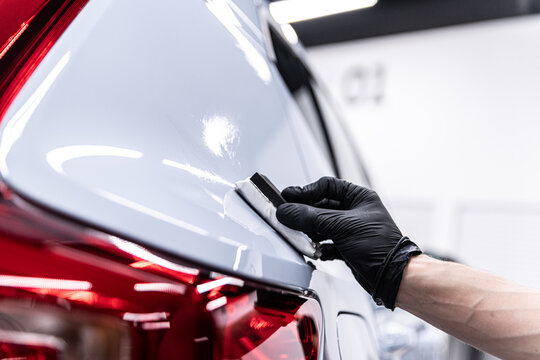 Close-up of ceramic coating being applied to a rear car body panel near the taillight by a gloved detailer, highlighting precision work, paint protection and premium car detailing service.