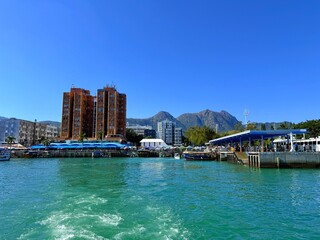 Fototapeta premium Sai Kung Harbour and Waterfront with Boats and Mountain Views in Hong Kong on a Clear Day and at Sunset