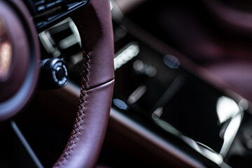 Close-up of precise stitching on a leather steering wheel inside a modern luxury car, highlighting craftsmanship, material quality and premium automotive interior design.