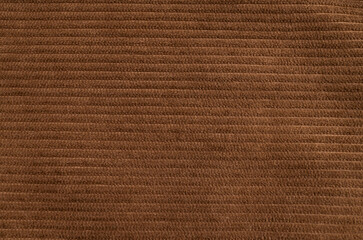 Close-up of texture of brown ribbed cotton corduroy fabric. Abstract textile background, warm and...