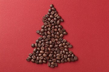 Coffee beans forming christmas tree on red background, copy space