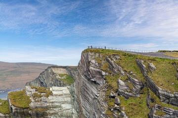 View of the Kerry Cliffs along the coastline of Kerry, Ireland and the North Atlantic Ocean with some people standing on the highest point of the cliffs © Sonja