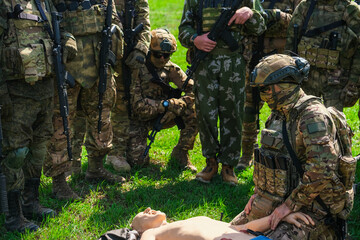 Military man dressed in camouflage puts a turnstile on an artificial limb of a mannequin and practices first aid skills in extreme conditions