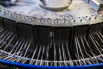 There are many large spools of white thread on the shelves, which are used in textile production