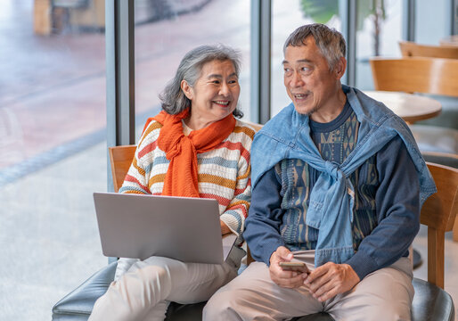 elderly people with modern lifestyle,bonding asian senior couple sitting in coffee shop,old man using smartphone surfing internet online and a woman using laptop to work