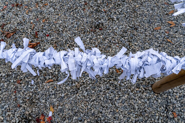 Shredded paper strands on a line above gravel ground during a quiet outdoor setting