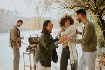 Friends enjoy a cheerful gathering by the serene lake on a sunny autumn day