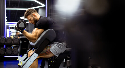 Muscular man lifting dumbbell in modern gym during workout session