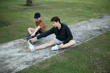 A young LGBT couple stretches together outdoors, enjoying a healthy workout routine in a peaceful neighborhood park