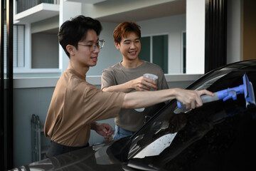 A cheerful gay couple works side by side cleaning their car, turning a simple chore into a fun and loving shared activity
